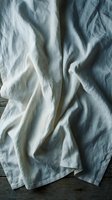 Soft gray linen fabric with natural wrinkles and folds creating organic texture patterns on wooden surface for interior design and textile backgrounds.