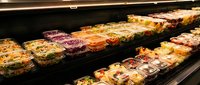 Fresh prepared salads and meal containers displayed in refrigerated grocery store deli section with variety of healthy options for convenient shopping.