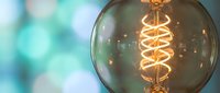 Vintage Edison bulb with glowing spiral filament against soft bokeh background for modern interior design and lighting concepts.