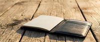 Two blank notebooks with brown and black covers lying open on rustic wooden planks, showcasing natural textures for creative writing and planning projects.
