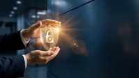 Businessman hands protecting glowing security shield with lock icon representing cybersecurity, data protection and digital safety in modern office environment.