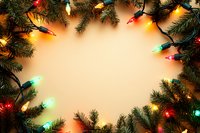 Festive frame of glowing multicolored Christmas lights and evergreen pine branches against warm beige background creating magical holiday border with copy space.