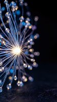 Glowing fiber optic strands with luminous bokeh spheres radiating from bright center point against dark background, representing technology, connectivity, data transmission, and digital innovation concepts.