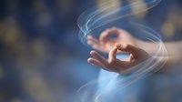 Hand gesture with flowing light trails and energy streams creating magical motion effects for meditation and spiritual wellness concepts.