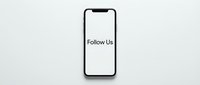 Smartphone with Follow Us text on screen, minimalist flat lay on white background, social media marketing concept.