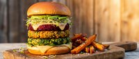 Gourmet plant-based burger with multiple patties, fresh greens and sweet potato fries on wooden board. Vegan fast food meal for healthy dining and restaurant menu.