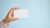Hand holding blank white business card against light blue background, ready for custom branding and corporate identity design.