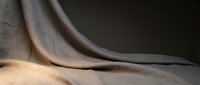 Elegant flowing fabric drapes creating soft curves and shadows against neutral background for luxury textile and interior design projects.