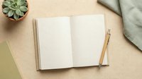 Open notebook with blank pages, wooden pen, succulent plant in pot, and green fabric on beige background, styled for stationery, planning, and creative workspace design projects.