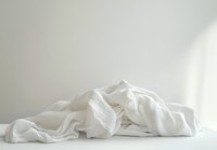 Crumpled white fabric with soft folds and gentle shadows against light background creates minimalist composition with delicate texture and ethereal mood.