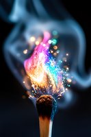 Burning match with magical multicolored flame and smoke effect against dark background, sparks and bokeh creating mystical atmosphere for creative designs.