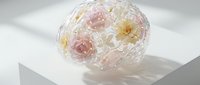 Transparent glass sphere with delicate pink and yellow flowers inside, artistic floral arrangement on white background for modern home decor and design projects.