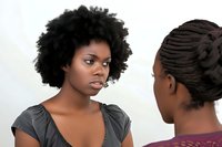 Young African American woman with natural afro hairstyle in serious conversation with another person, showing emotional expression and authentic interaction.