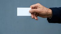 Male hand holding blank white card against blue background, suitable for business cards, contact information, or promotional messaging.