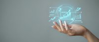 Hand holding glowing holographic business analytics interface with charts, graphs and upward arrows representing financial growth and data analysis.