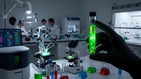 Scientist in black gloves holding green fluorescent test tube in modern laboratory with microscopes and research equipment for medical analysis.