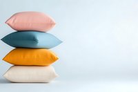 Stack of colorful decorative pillows in pink, teal, yellow and cream shades arranged on white background, minimalist home decor composition.