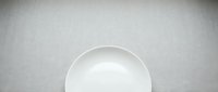 Empty white bowl on gray textured surface, minimalist tableware setup for food styling, culinary presentations, restaurant menus, and kitchen design projects.