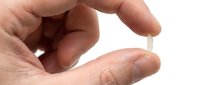 Young adult hand holding clear contact lens on fingertip against white background, ready for eye care application or vision correction demonstration.