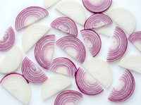 Sliced red onion halves scattered on a white background, showing layers and texture, isolated for food and cooking content.