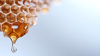 Golden honeycomb with fresh honey dripping, macro shot showing detailed hexagonal wax cells structure and liquid drop on light background. Natural organic sweetener.