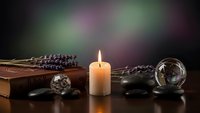 Mystical fortune telling setup with burning candle, crystal ball, tarot cards and lavender sprigs creating atmospheric divination scene for spiritual guidance.