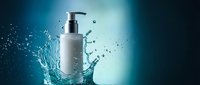 White cosmetic pump bottle with water splash on blue gradient background for skincare and beauty product advertising.