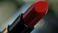 Vibrant red lipstick in black tube, close-up macro shot with soft bokeh background, showcasing glossy cosmetic product for beauty and makeup industry.