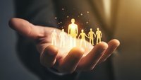 Businessman hands holding glowing family figures with sparkling light effects representing life insurance protection and family care services.