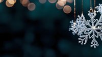 Sparkling silver snowflake ornaments hanging with warm bokeh lights creating magical winter holiday atmosphere for festive seasonal decorations.