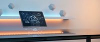 Futuristic holographic tablet displaying cloud computing interface with floating geometric elements in modern workspace environment.
