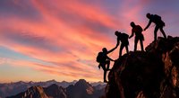 Team of climbers helping each other reach mountain summit at sunset with dramatic pink and orange sky over alpine peaks creating inspiring teamwork scene.