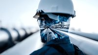 Double exposure portrait of industrial worker with safety helmet overlaid with oil pipeline facility in blue tones, representing energy industry.