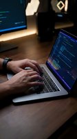 Software developer coding on laptop with programming interface in modern workspace environment for technology projects.