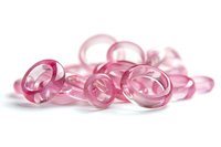 Translucent pink plastic rings scattered on white background, macro photography with soft focus and shallow depth of field creating dreamy aesthetic effect.