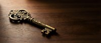 Ornate vintage brass key with decorative scrollwork lying on dark wooden surface, symbolizing mystery, secrets, and unlocking opportunities.