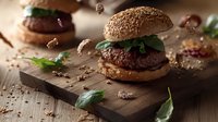 Juicy beef burger with sesame bun and fresh spinach leaves on rustic wooden board, flying sesame seeds and dramatic lighting for food photography.