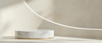 Minimalist marble podium with gold accent on neutral beige background with soft shadows and curved architectural elements for luxury product display.