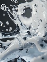 Dynamic water splash captured in macro photography against dark background shows crystalline liquid formations and airborne droplets in monochromatic tones.