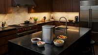Modern luxury kitchen with dark granite countertops, wooden cabinets, marble backsplash and stainless steel appliances for contemporary home design.