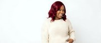 Young African American woman with burgundy red hair wearing cream knit sweater smiling joyfully on white background isolated for design use.
