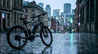 Electric bike parked on wet cobblestone street in urban downtown area with modern skyscrapers in background, suitable for transportation and eco-friendly commuting concepts.