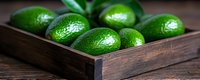 Fresh ripe green limes in rustic wooden box on dark background. Natural citrus fruits with textured skin arranged in vintage container for food styling.