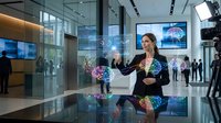 Young Caucasian businesswoman in suit interacting with glowing holographic brain interfaces in modern corporate office, AI technology concept.