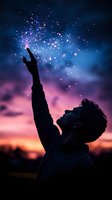 Silhouette of young man reaching towards magical sparkles in twilight sky with vibrant purple and orange sunset colors creating dreamy atmosphere.