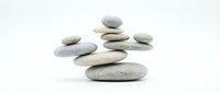 Balanced stone cairns stacked in zen meditation arrangement on white background for wellness spa and mindfulness concepts.