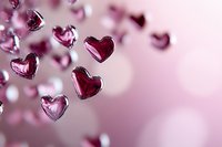 Floating pink glass hearts on blurred romantic background create dreamy atmosphere for Valentine's Day designs and love-themed projects.