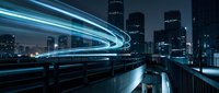 Futuristic city skyline at night with glowing blue light trails from fast moving traffic creating dynamic motion blur effects against illuminated skyscrapers.