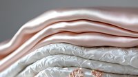 Luxurious layered silk and satin fabrics in rose gold and ivory white with delicate damask pattern create elegant wedding or fashion background texture.