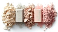 Crushed makeup powder palette showing gradient transition from ivory to gray and pink shades, with rectangular pressed powder samples on white background.